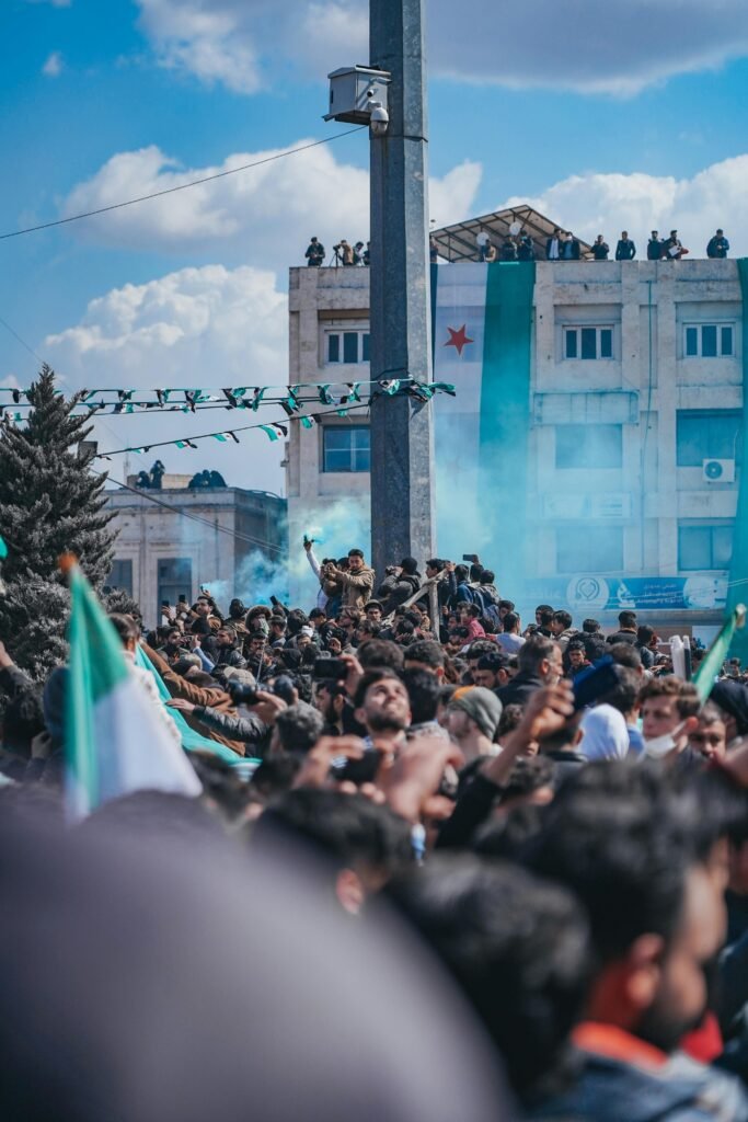 A large crowd gathered for a protest in Syria, waving national flags and banners.