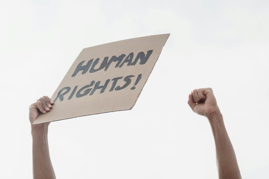 Raised clenched fists holding a sign advocating for human rights in a protest setting.